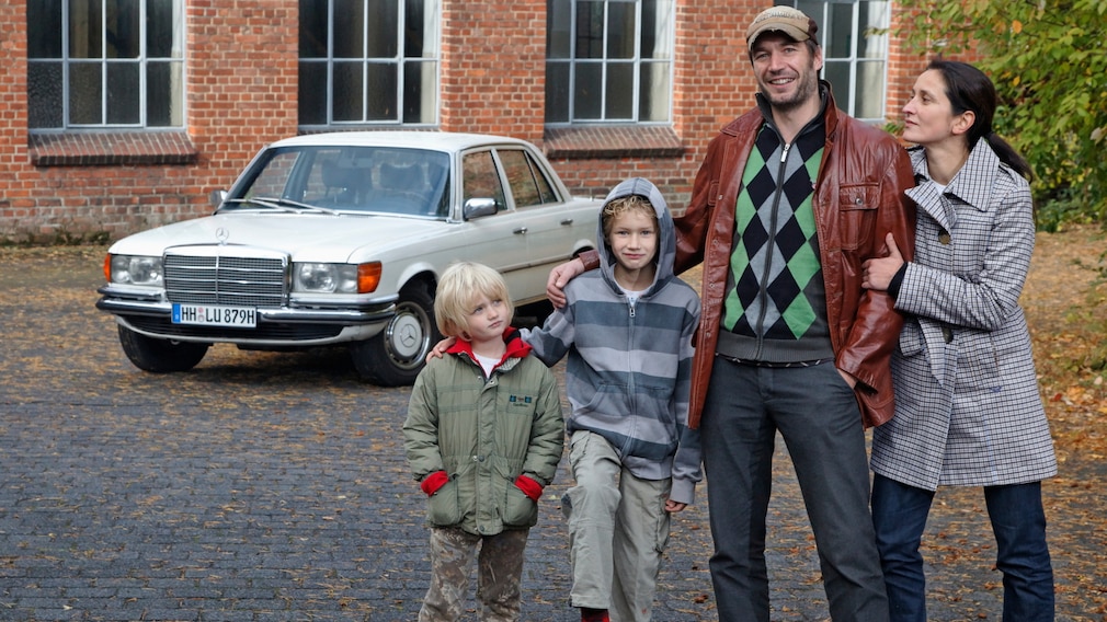 Familei (Vater, Mutter, zwei Kinder) steht vor einer Mercedes S-Klasse (W 116)