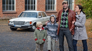 Familei (Vater, Mutter, zwei Kinder) steht vor einer Mercedes S-Klasse (W 116)