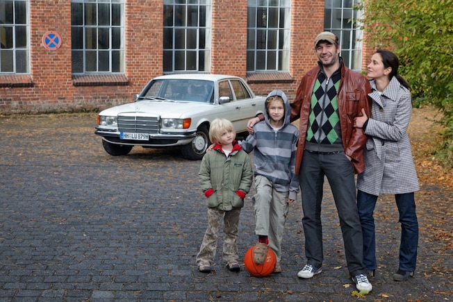 Familei (Vater, Mutter, zwei Kinder) steht vor einer Mercedes S-Klasse (W 116)