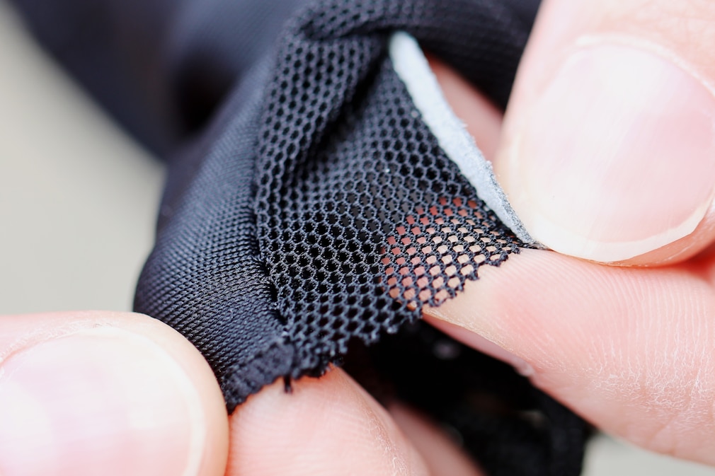Das luftdurchlässig-perforierte Material des Vaudes zwischen den Fingern.