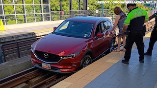 Frau fährt ihren Mazda auf die Bahngleise