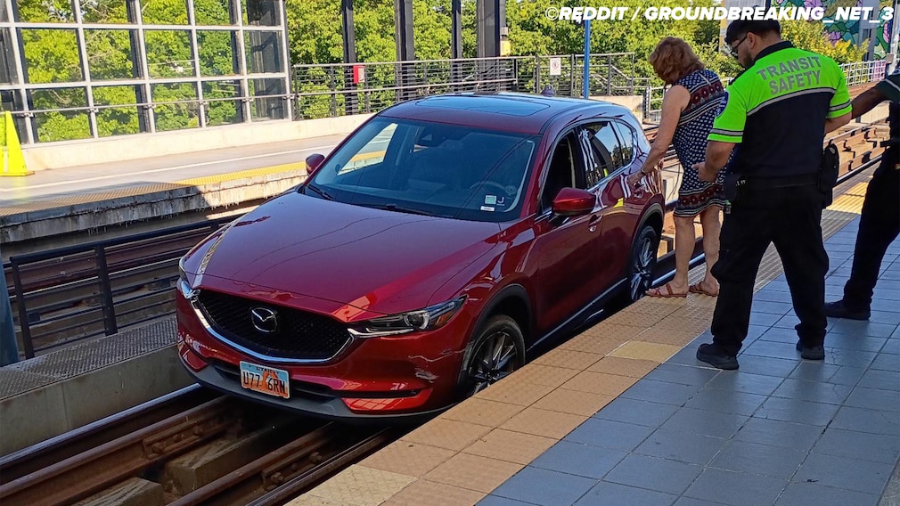 Frau fährt ihren Mazda auf die Bahngleise