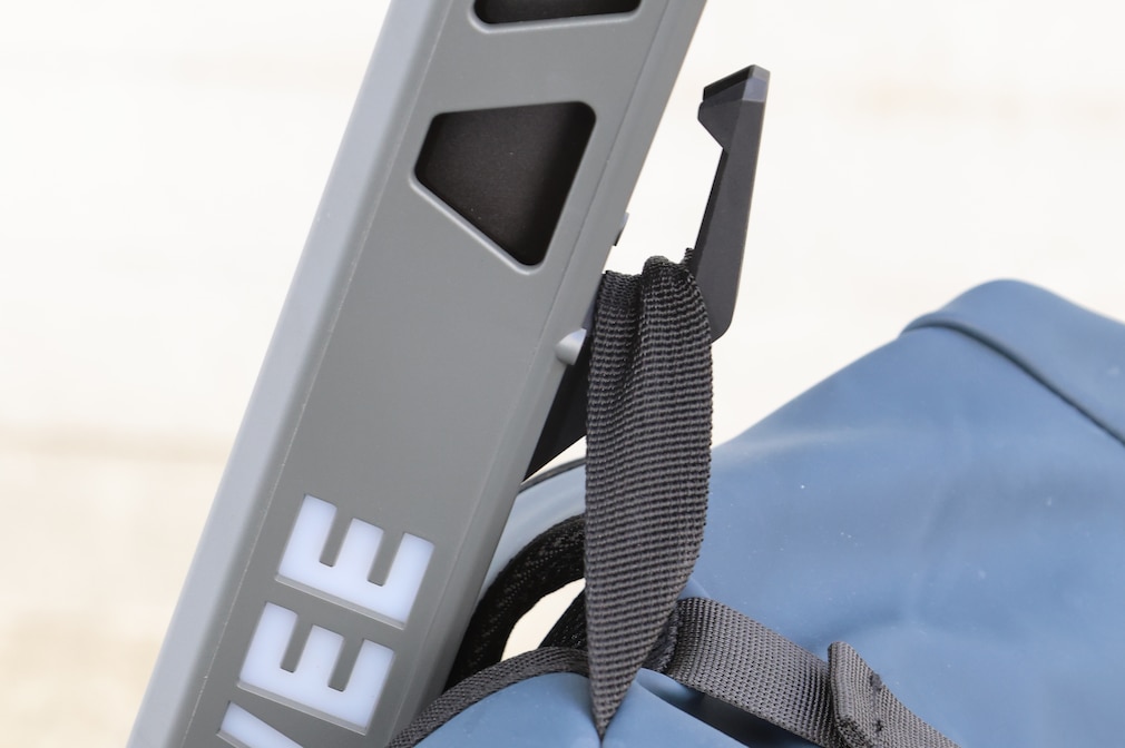 Detailaufnahme des mittig an der Lenkstange angebrachten Taschenhakens mit eingehängtem Rucksack.