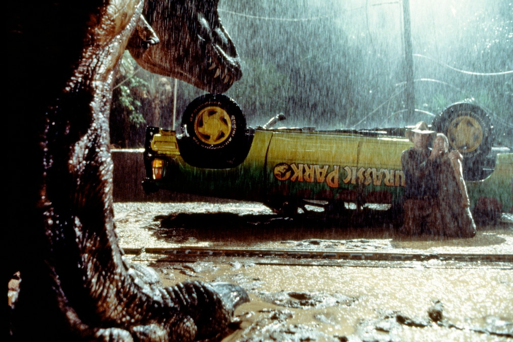 Filmszene auzs "Jurassic Park" 1993 mit Dinosaurier und Ford Explorer, der auf dem Dach liegt