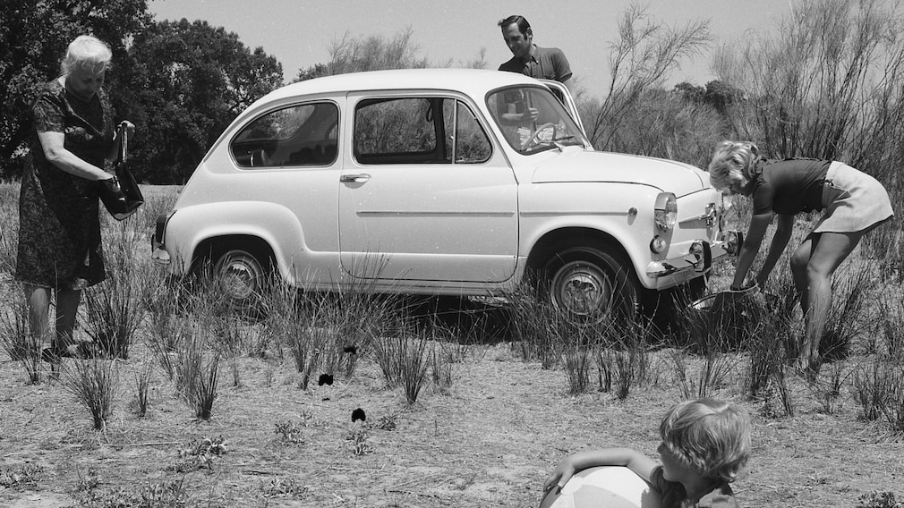 Historisches Schwarzweißfoto von 1969: spanisches Ehepaar mit Seat 600, Kind und Oma beim Ausflug