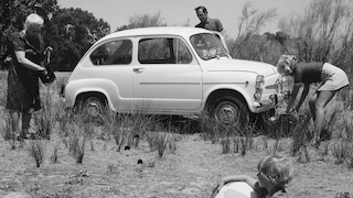 Historisches Schwarzweißfoto von 1969: spanisches Ehepaar mit Seat 600, Kind und Oma beim Ausflug