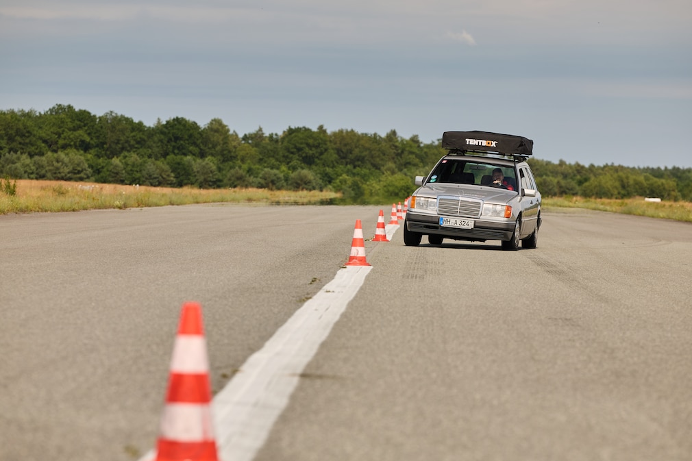 Mercedes T-Modell der Baureihe 124 fährt mit montiertem Dachzelt einen Slalom
