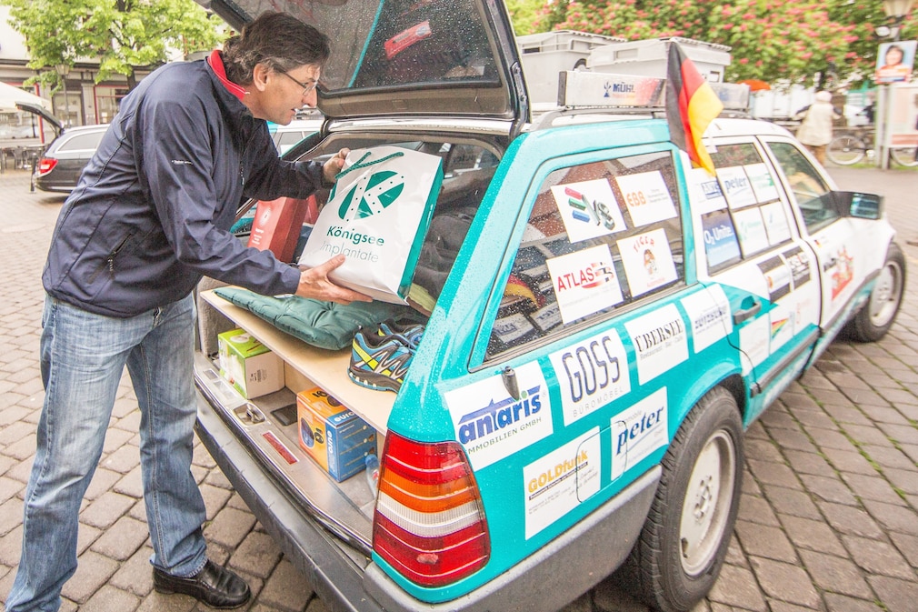 Mann packt Tüte in einen fast vollbeladenen Mercedes S 124 (Mercedes W124 Kombi T-Modell), Allgäu-Orient-Rallye 2014