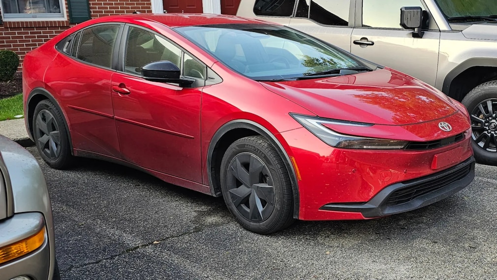 Toyota Prius LE in rot geparkt vor einem Backsteinhaus.