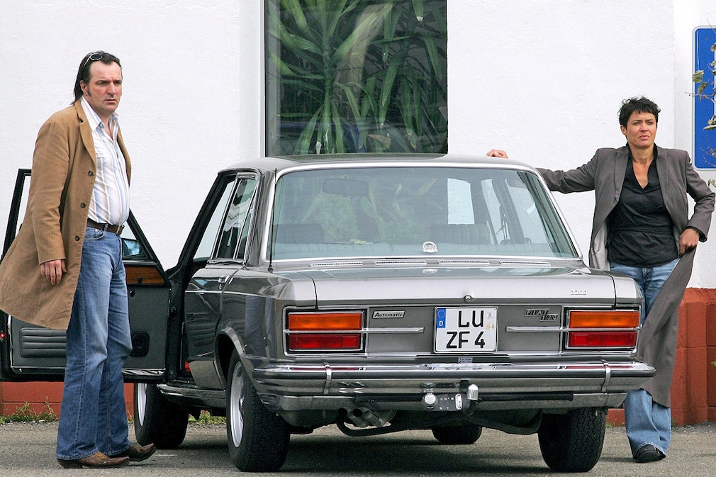 Die Schauspieler Andreas Hoppe und Ulrike Folkerts posieren am Donnerstag (07.04.2005) in einer Fabrikhalle in Karlsruhe bei Dreharbeiten zum SWR-Tatort mit dem Titel Unausweichlich für die Fotografen neben ihrem Dienstwagen Fiat 130 Limousine