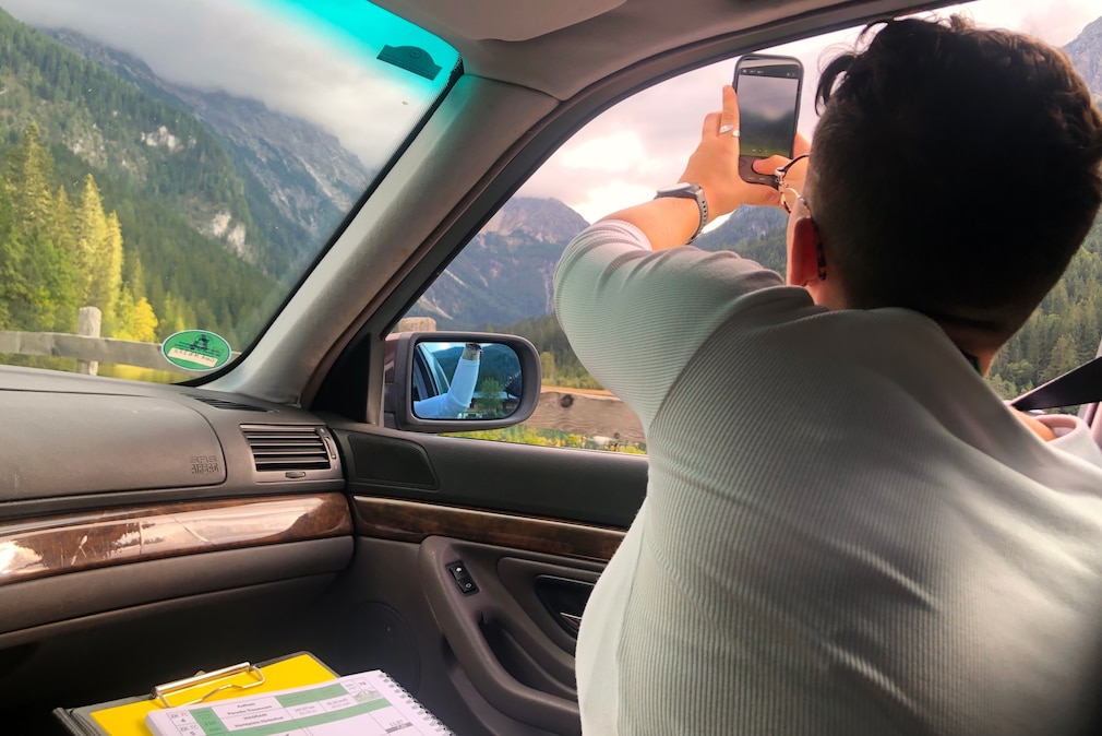 Beifahrerin macht mit dem Handy Fotos aus der Seitenscheibe heraus
