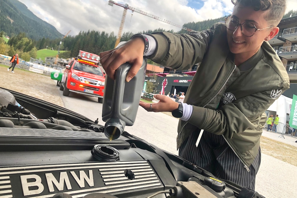 Junge Frau füllt Motoröl in einen Motor mit BMW-Aufschrift auf dem Ventildeckel
