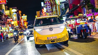 VW ID.Buzz bei der Weltumrundung auf einer nächtlichen Straße in einer thailändischen Großstadt.