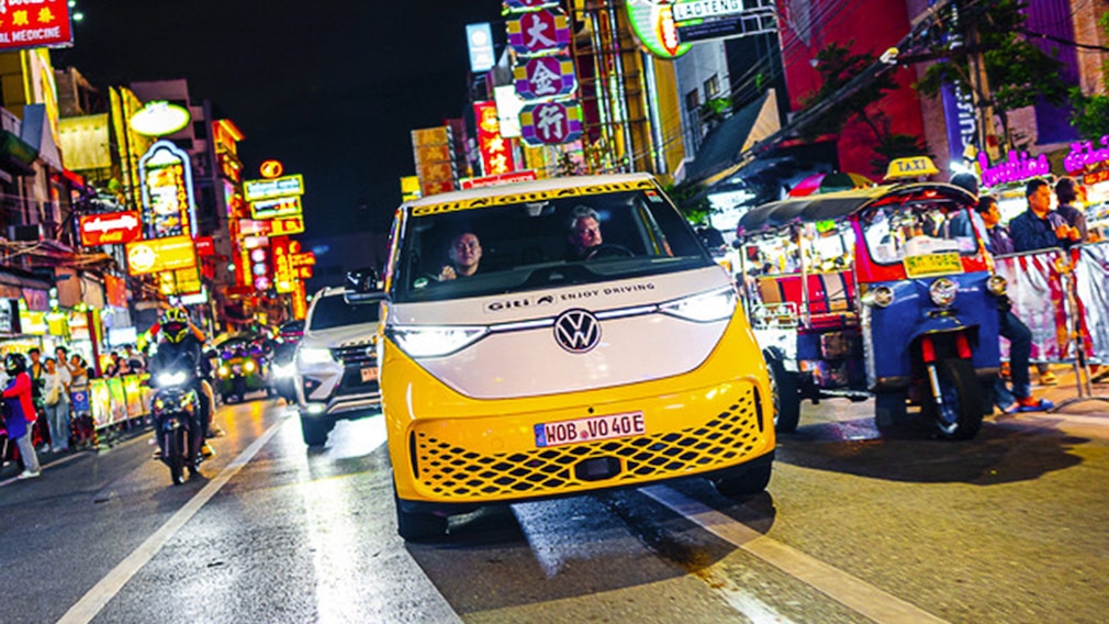 VW ID.Buzz bei der Weltumrundung auf einer nächtlichen Straße in einer thailändischen Großstadt.