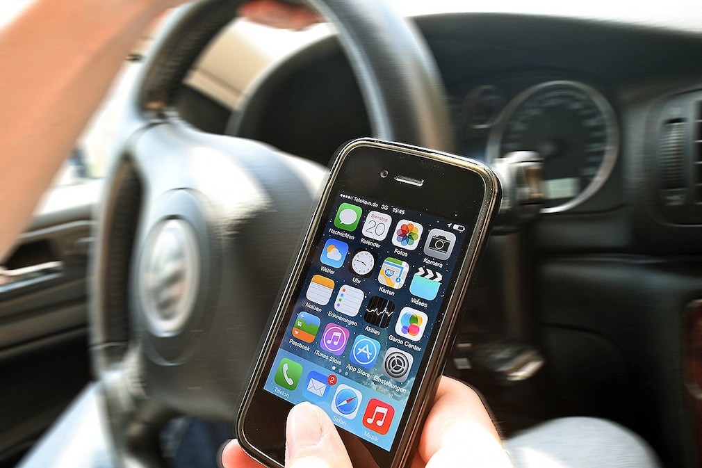 Eine Hand am Smartphone, die andere am Lenkrad des Fahrzeuges, fotografiert am 20.05.2014 in Hannover (Niedersachsen). Mit einer Plakataktion will die Landesverkehrswacht Niedersachsen vor SMS-Schreiben oder Handysurfen am Steuer warnen. Foto: Holger Hollemann/dpa (zu lni "Kampagne gegen SMS-Tippen am Steuer" vom 21.05.2014)