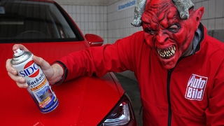 AUTO BILD-Redakteur mit Teufelsmaske und Backofenspray am Auto