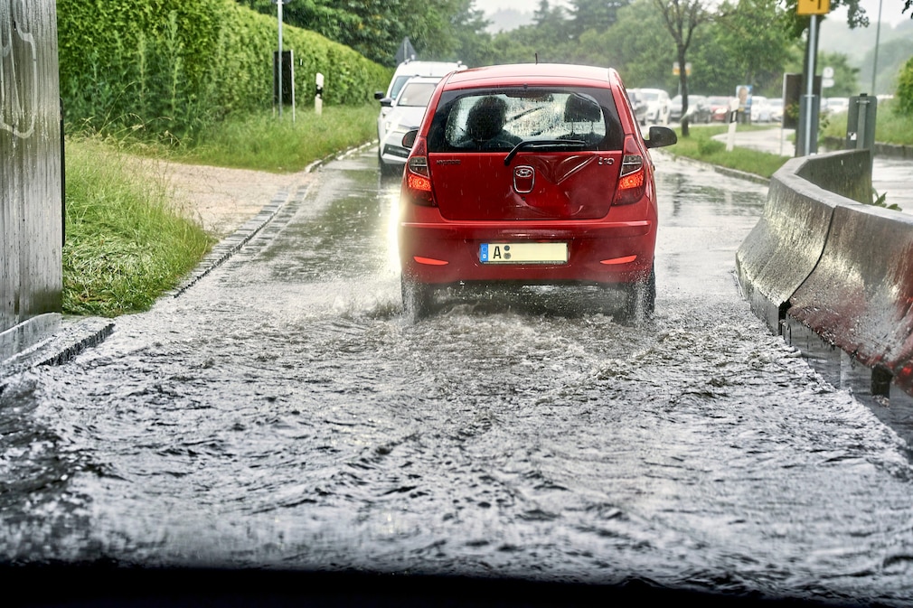 Hochwasser nach Dauerregen bzw. Starkregen in Bayern, Wassermassen durch Regen auf den Stra§en und berflutete Wege und Durchfahrten, Autos kommen kaum noch durch