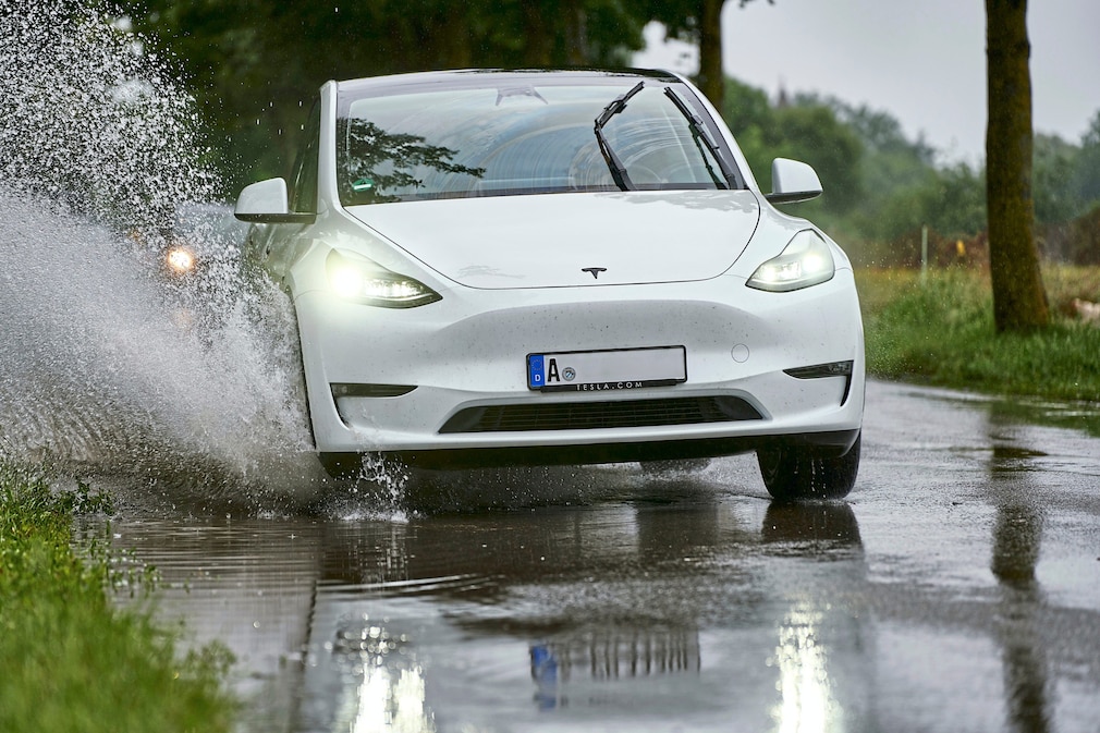 E-Auto von Tesla fhrt durch eine berflutete Stra§e in Augsburg