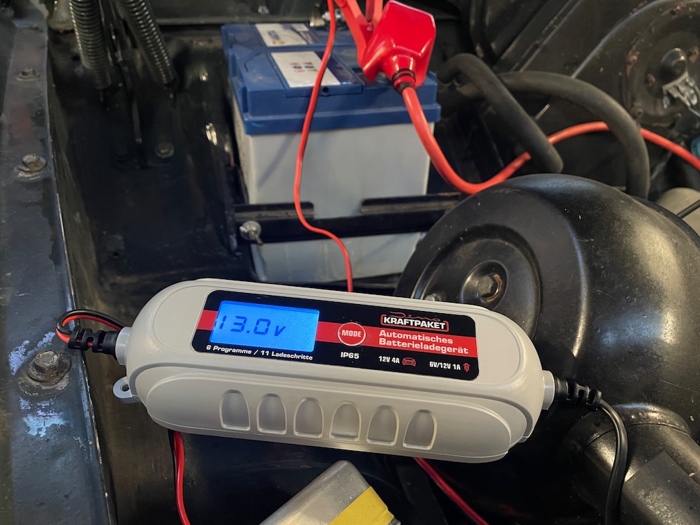 Nahaufnahme: Digital-Display eines Ladegerätes, liegend in offenem Motorraum.