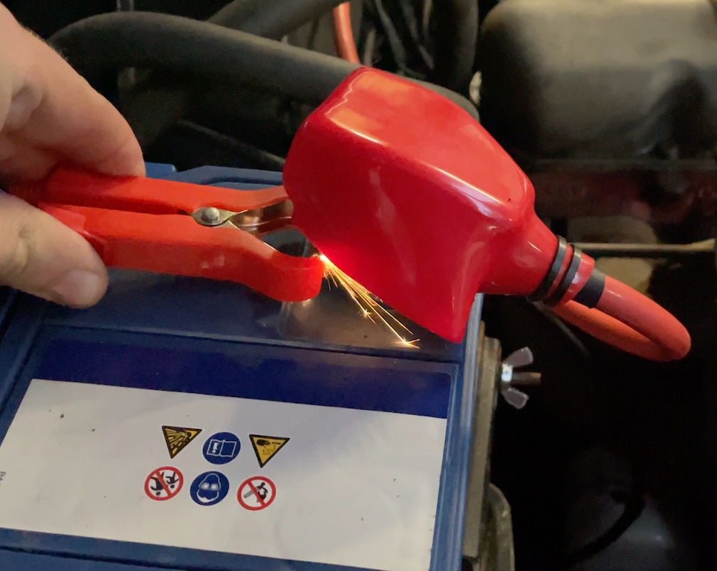 Nahaufnahme: Sprühende Funken an Batterieanschlussklemme beim Verbinden mit dem Ladegerät.