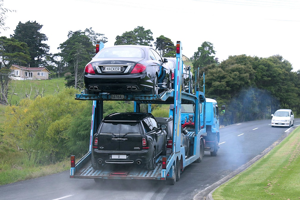 Verschiedene Autos werden am Freitag (20.01.2012) in Neuseeland auf einem Transporter von einem Grundstück in Coatesville, 300 Kilometer nordwestlich von Auckland im Bezirk North Shore, abtransportiert