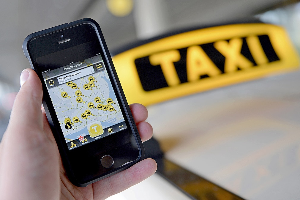Ein Smartphone mit der geˆffneten App MyTaxi wird am 03.09.2014 am Flughafen in Hamburg vor das Schild eines Taxis gehalten. Die Daimler-Tochter Moovel ¸bernimmt den Betreiber der Taxivermittlungs-App MyTaxi, die Intelligent Apps GmbH aus Hamburg. Foto: Daniel Reinhardt/dpa